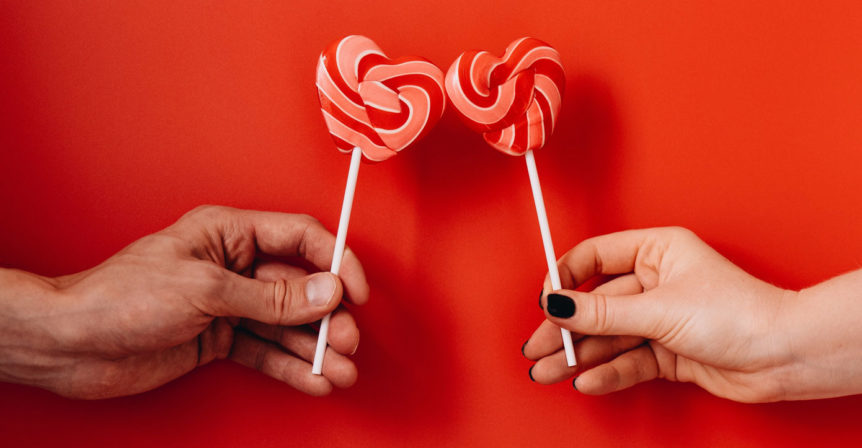 Decorative Image of two heart shaped candies held together by different people